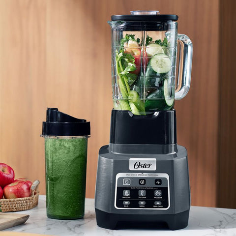OSTER LIC XTREME MIX C/VASO BLSTXPG-BGW with glass blender jar and Blend-N-Go cup, featuring vegetables inside.