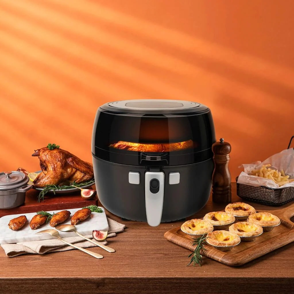 Freidora de aire C/VIDRIO 7.0L 1350W KUEC041B Decakila con comida cocinada en una mesa de madera y fondo anaranjado.
