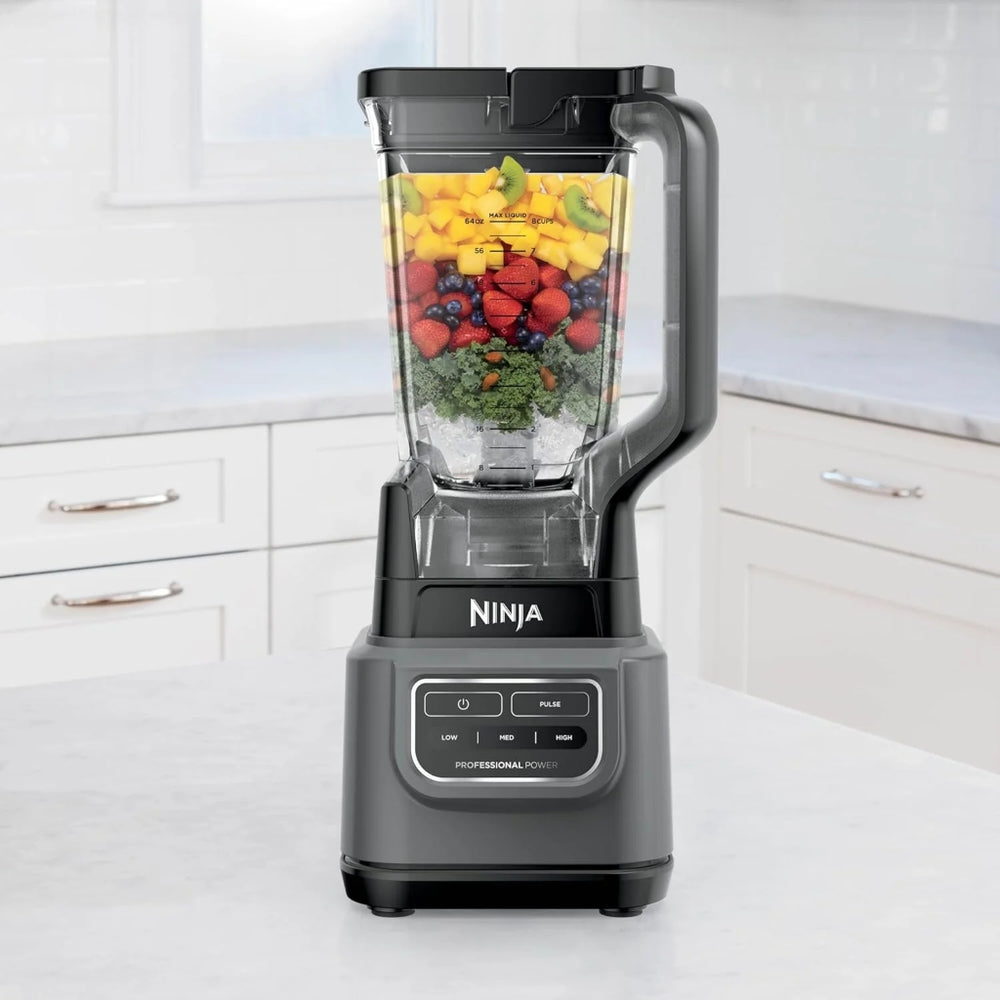 Licuadora Ninja Clásica 1000W en cocina moderna con frutas variadas en el vaso. Potente motor y sistema de 6 aspas para un licuado eficiente.